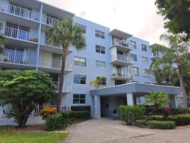 a front view of a multi story residential apartment building with a yard and potted plants