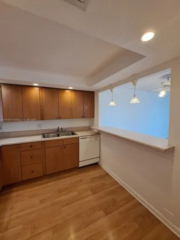 a view of an empty room with wooden floor and chandelier