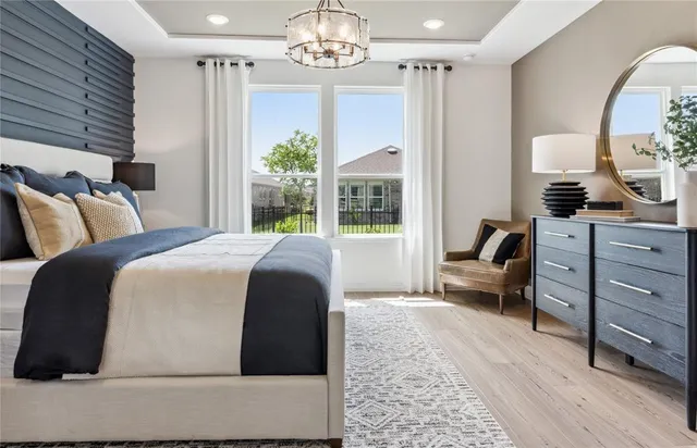 a spacious bedroom with a bed a chandelier and a dresser
