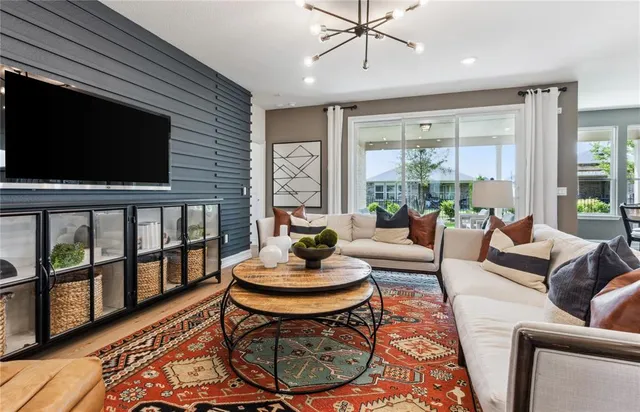 a living room with furniture a flat screen tv and a floor to ceiling window