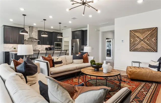 a living room with furniture kitchen view and a chandelier