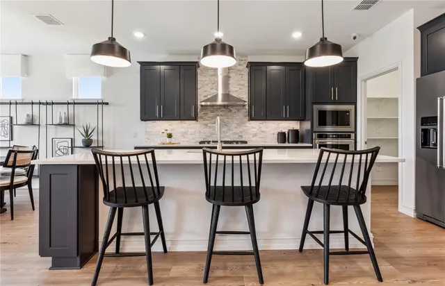 a kitchen with stainless steel appliances kitchen island granite countertop a dining table chairs and a view of living room