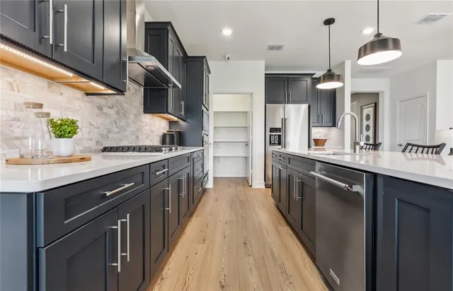 a kitchen with stainless steel appliances granite countertop a sink a stove and a wooden floors