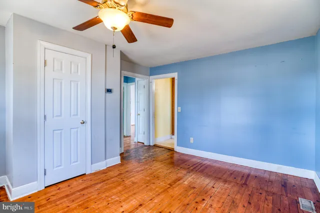 a view of a room with wooden floor and a ceiling fan