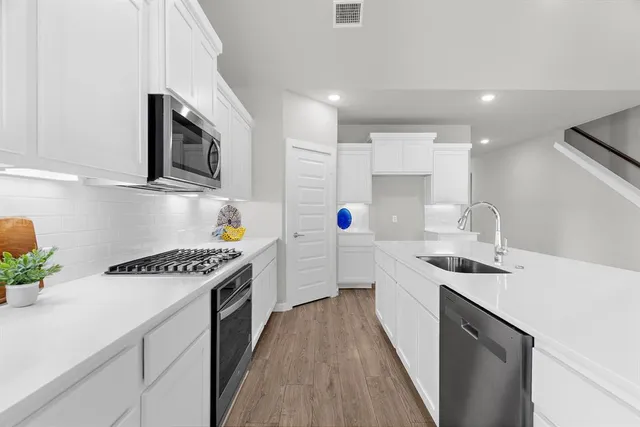 a kitchen with stainless steel appliances granite countertop a sink stove and cabinets