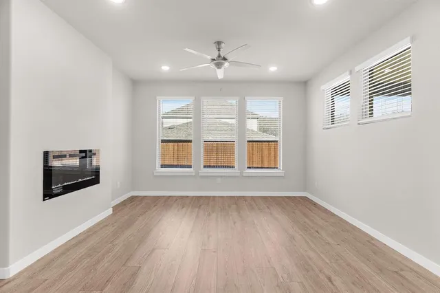 a view of an empty room with a window and wooden floor
