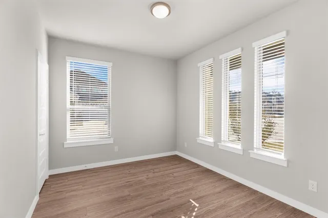 a view of an empty room with wooden floor and a window
