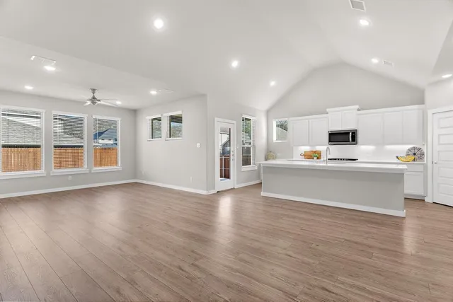a view of a kitchen with kitchen island wooden floors and stainless steel appliances
