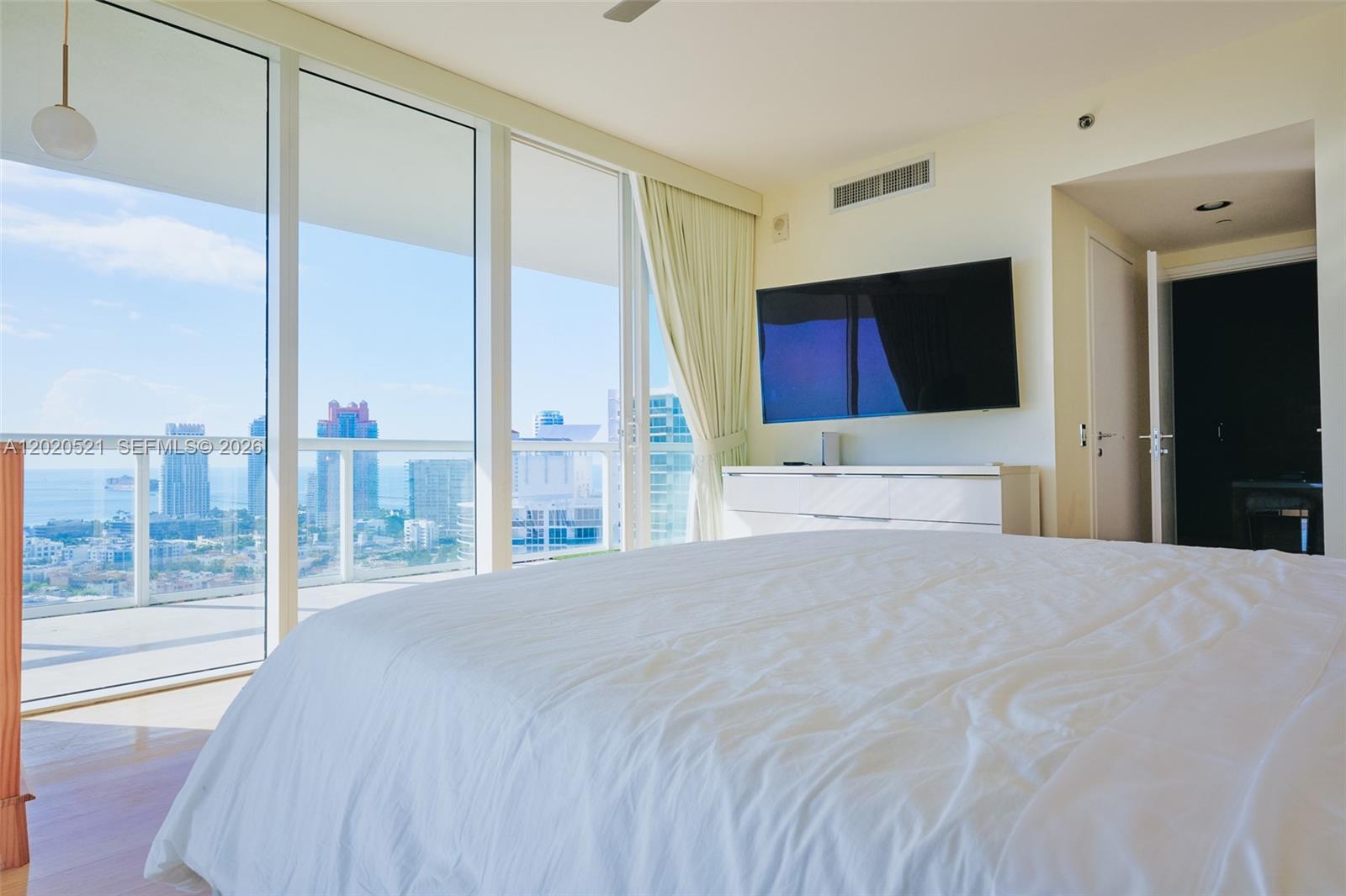 450 Alton Road, Unit 2810 Miami Beach, FL 33139 - Photo 12 of 29 a large bedroom with a large bed and a flat tv screen on dresser