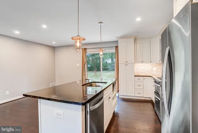 a kitchen with stainless steel appliances granite countertop a refrigerator a sink and a stove