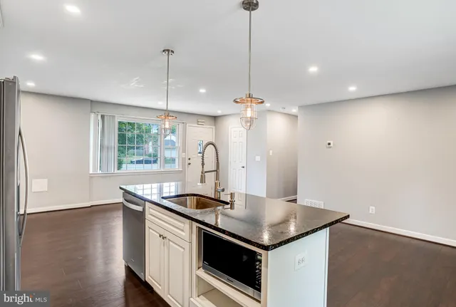 a kitchen with stainless steel appliances granite countertop a sink a window and wooden floor