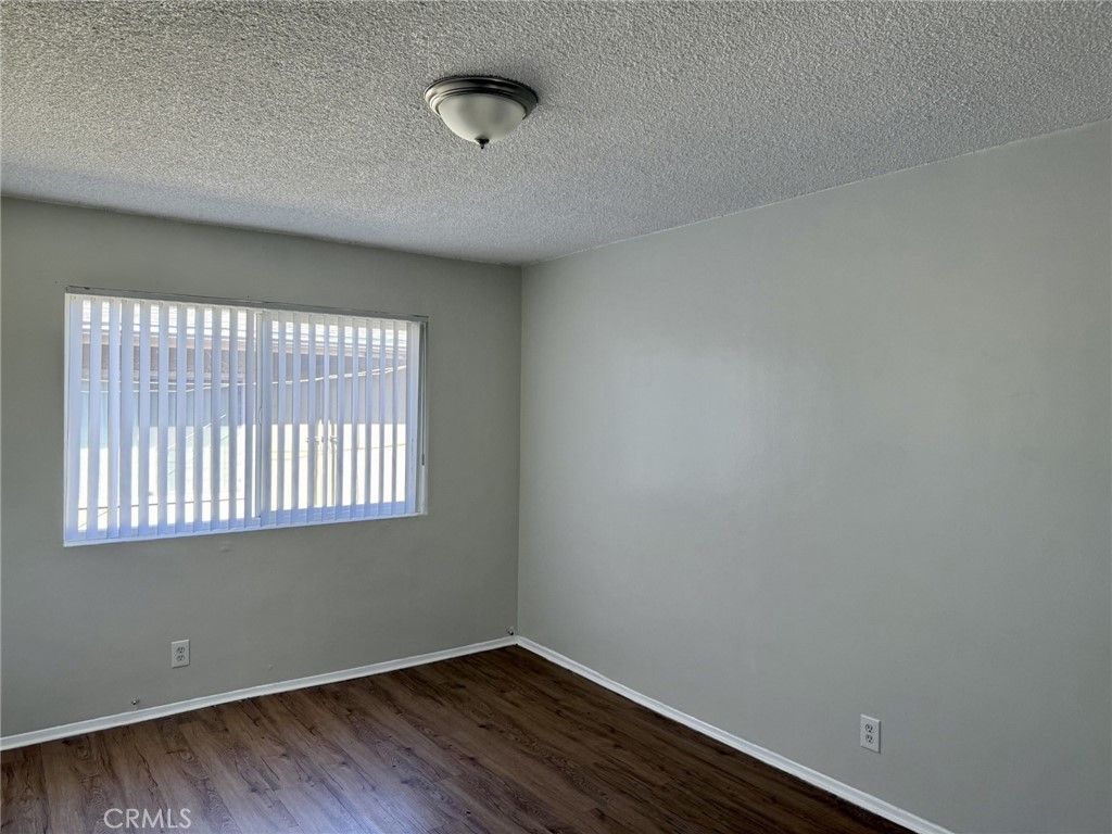 4830 Canoga Street, Unit J Montclair, CA 91763 - Photo 8 of 12 an empty room with wooden floor and windows