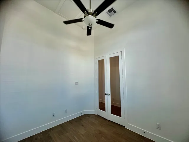 an empty room with wooden floor and fan