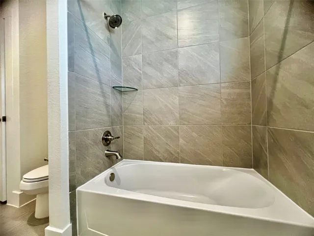 a bathroom with a white bath tub and a toilet