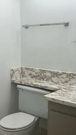 a bathroom with a granite countertop toilet sink and mirror