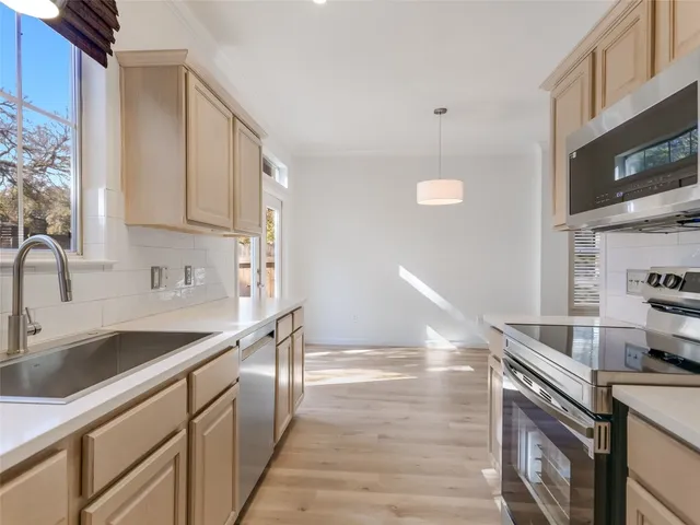 a kitchen with stainless steel appliances granite countertop a sink a stove and a microwave oven with cabinets