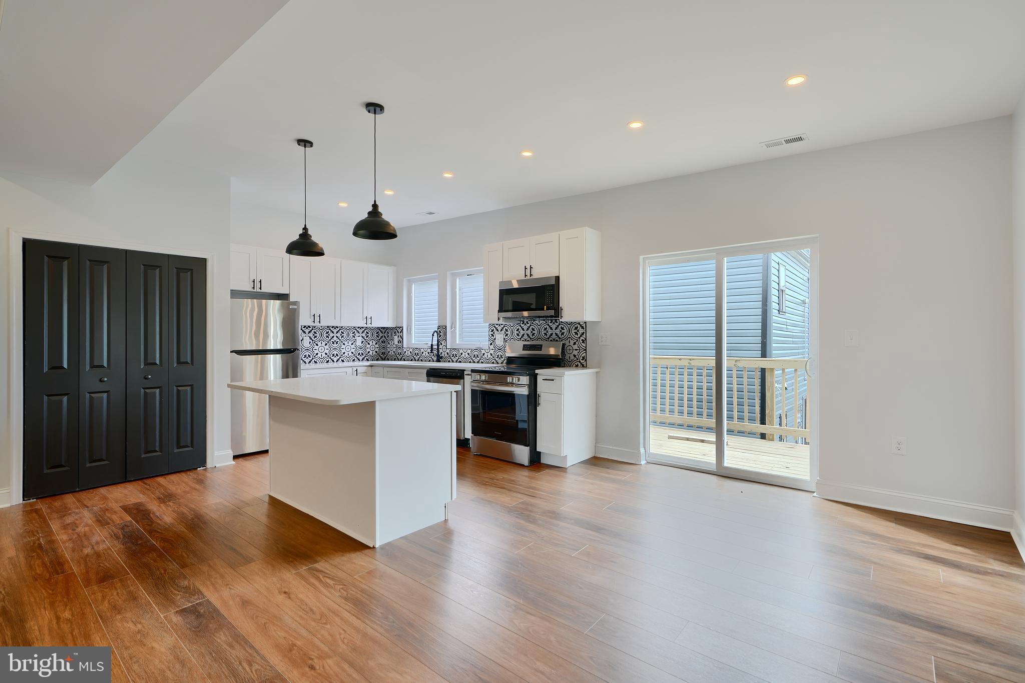 a kitchen with granite countertop a refrigerator oven a sink dishwasher and white cabinets with wooden floor