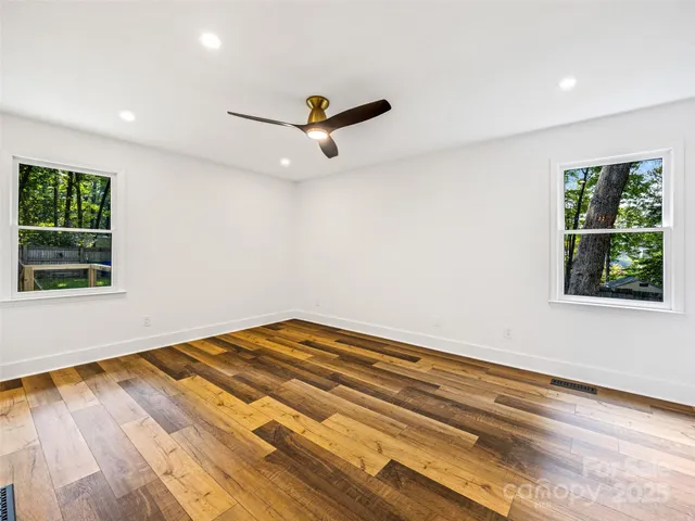 a view of empty room with wooden floor and fan