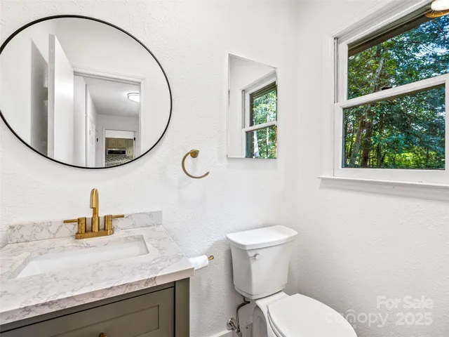 a bathroom with a granite countertop toilet sink and mirror