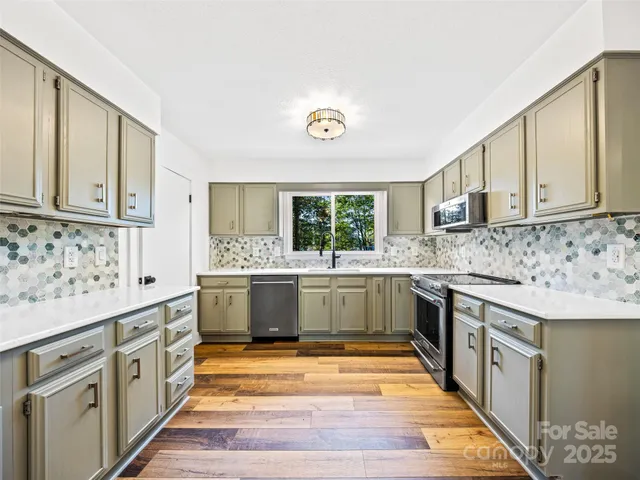 a large kitchen with stainless steel appliances granite countertop a stove a sink dishwasher and cabinets