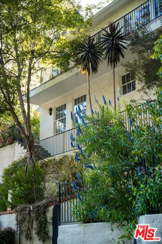 a view of a palm trees front of house with wooden fence