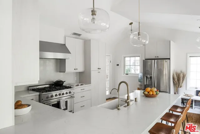 a kitchen with stainless steel appliances granite countertop a stove a refrigerator a sink dishwasher a dining table and chairs with wooden floor