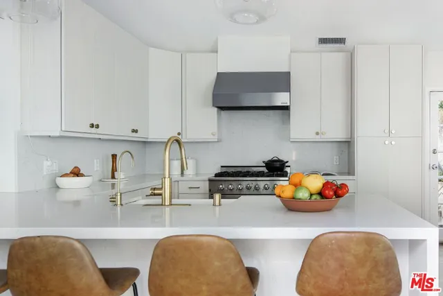 a kitchen with stainless steel appliances a sink a stove and white cabinets