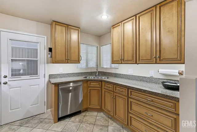 a kitchen with granite countertop stainless steel appliances a sink window and cabinets