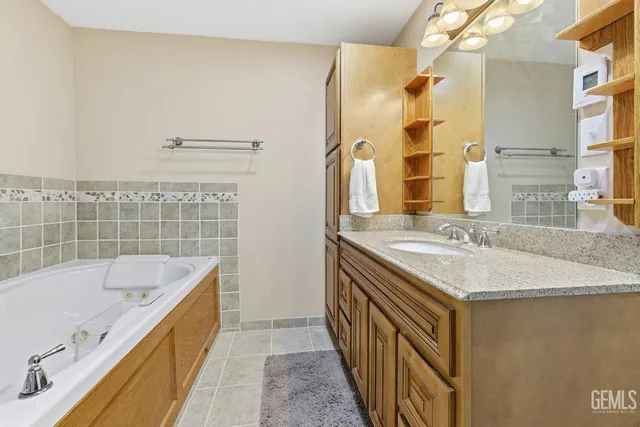 a bathroom with a granite countertop sink and a bathtub