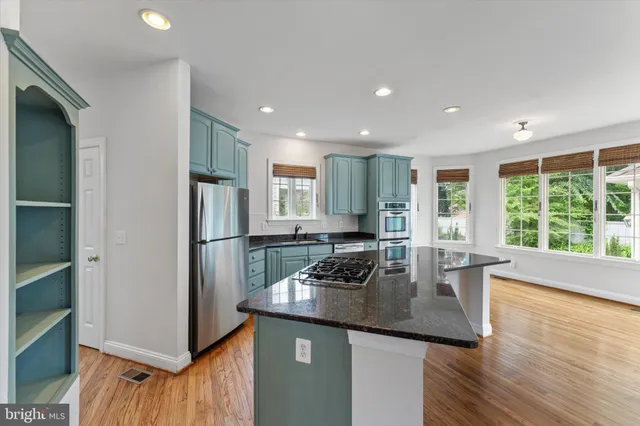 a kitchen with kitchen island a counter top space a sink a refrigerator and a large window
