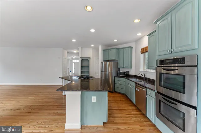 a kitchen with stainless steel appliances granite countertop a stove top oven a sink and a refrigerator