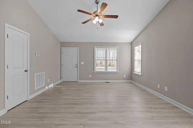 a view of an empty room with a window and wooden floor
