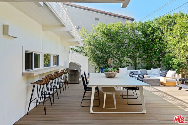a roof deck with table and chairs and potted plants