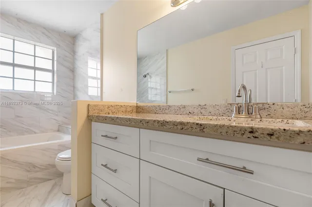 a bathroom with a granite countertop sink and mirror