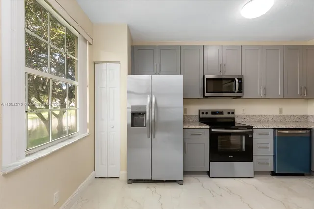 a kitchen with stainless steel appliances granite countertop a refrigerator and a stove top oven