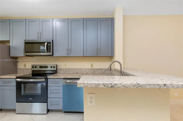 a kitchen with stainless steel appliances granite countertop a stove a sink and a microwave