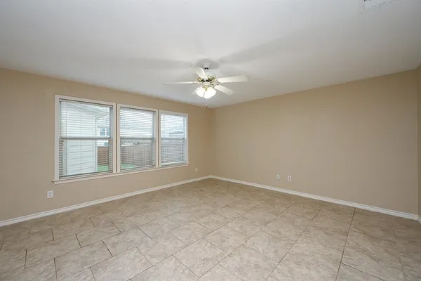 an empty room with chandelier fan and windows