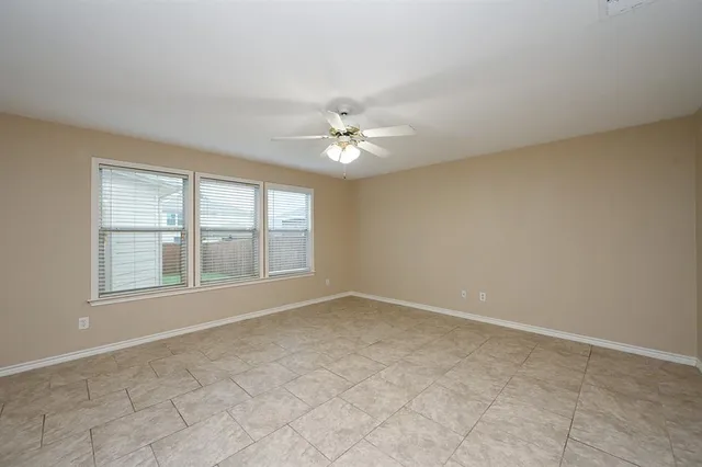 an empty room with chandelier fan and windows