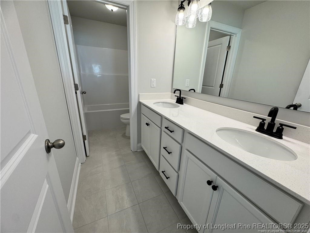 179 Grove Walk Road Raeford, NC 28376 - Photo 22 of 26 a bathroom with a double vanity sink a toilet and a mirror