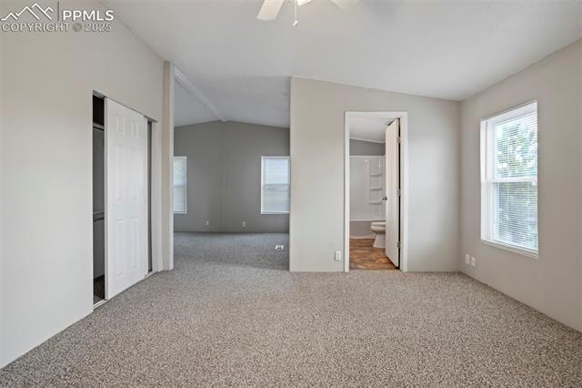 20150 Enoch Road Colorado Springs, CO 80928 - Photo 25 of 50 Unfurnished bedroom featuring carpet flooring, vaulted ceiling, ensuite bathroom, a closet, and a ceiling fan