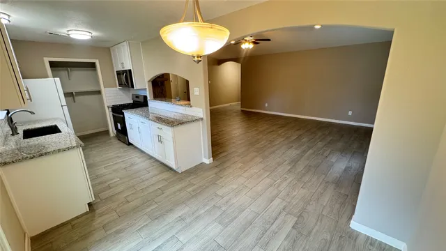 a view of a kitchen with kitchen island wooden floor center island and stainless steel appliances
