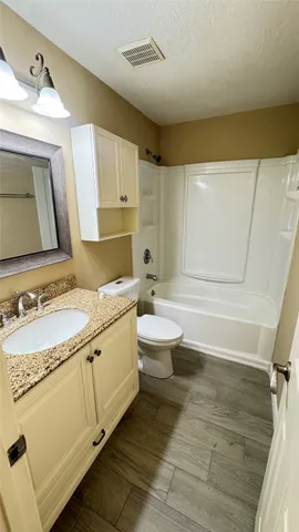 a bathroom with a granite countertop sink mirror vanity and toilet
