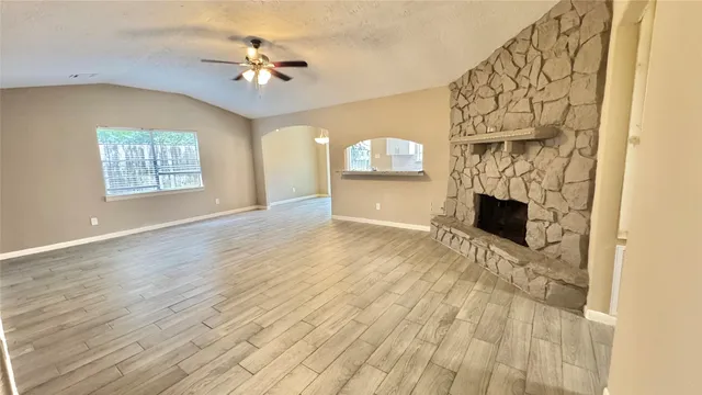 a view of empty room with a fireplace and wooden floor