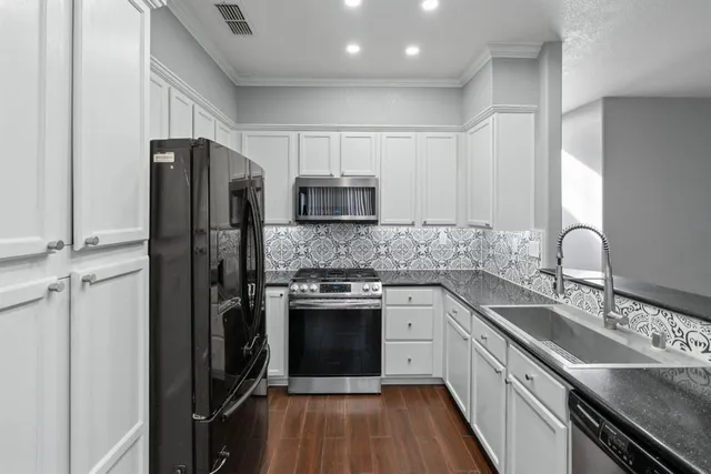a kitchen with a sink stainless steel appliances cabinets and a window