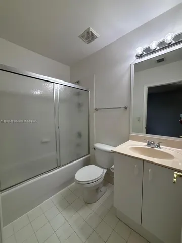 a bathroom with a granite countertop sink toilet mirror and a shower