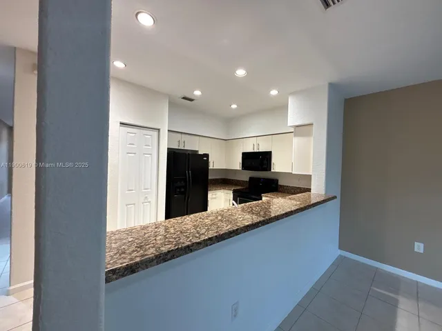 a large kitchen with granite countertop a sink and a large mirror