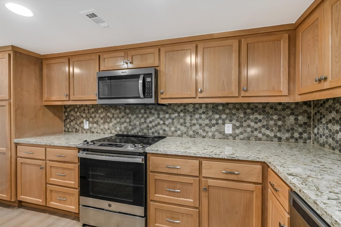 2918 Ranch Road 620 North, Unit B112 Austin, TX 78734 - Photo 5 of 10 Kitchen featuring stainless steel appliances, backsplash, light stone countertops, and light wood finished floors