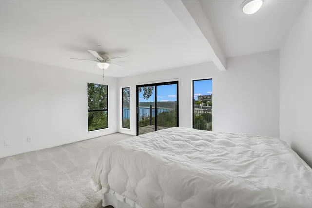 a large white bed in a room next to a large window