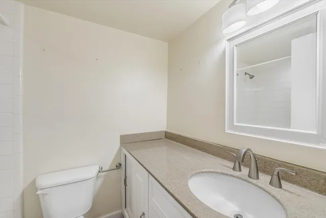 a bathroom with a granite countertop sink a toilet and a mirror