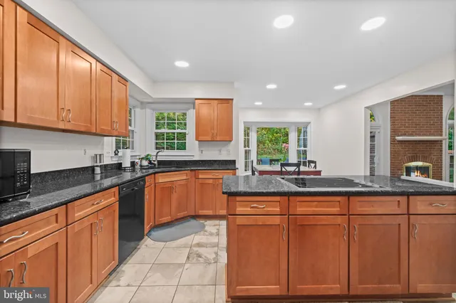 a kitchen with stainless steel appliances granite countertop a stove top oven a sink dishwasher a dining table and chairs with wooden floor